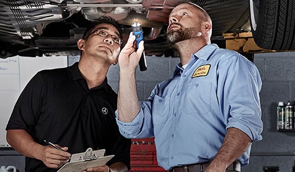 Service technicians inspecting bottom of vehicle